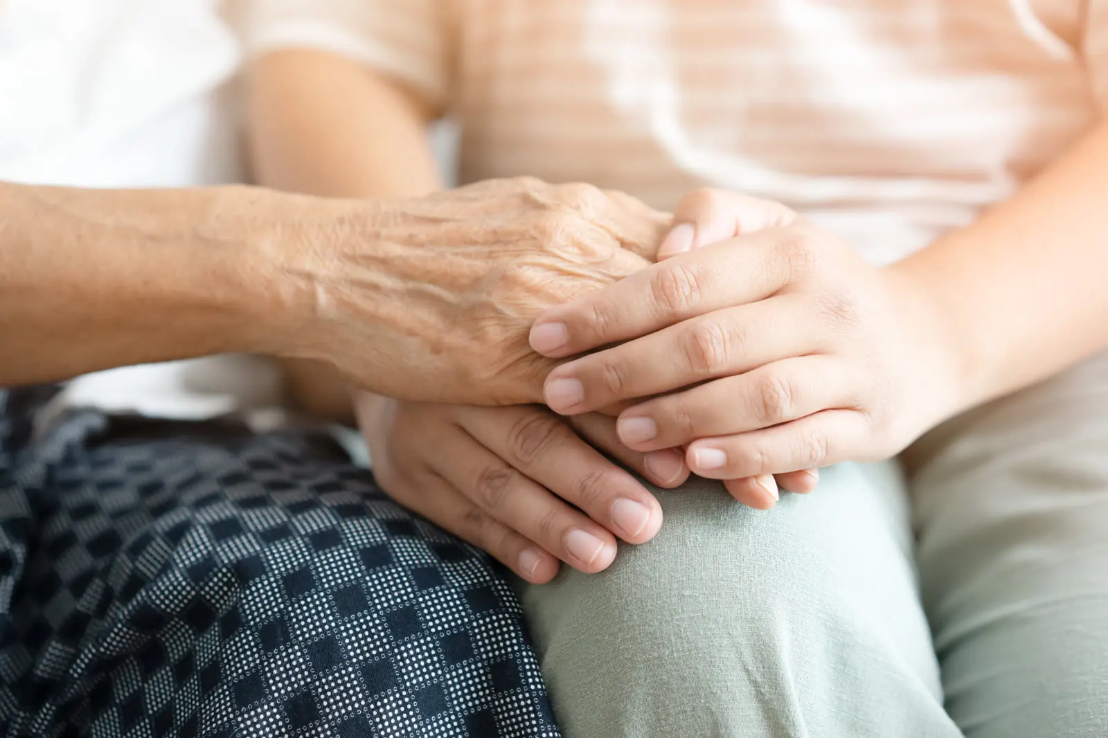 Eine Hand liegt haltend auf den Händen einer älteren Person